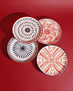 Set de 4 platos llanos con flores geométricas en rojo y azul, vista superior.
