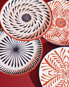 Platos llanos con motivos florales en rojo y azul, detalle de patrones concéntricos.