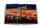 Libro abierto con foto de mercado nocturno con muchas telas y luces