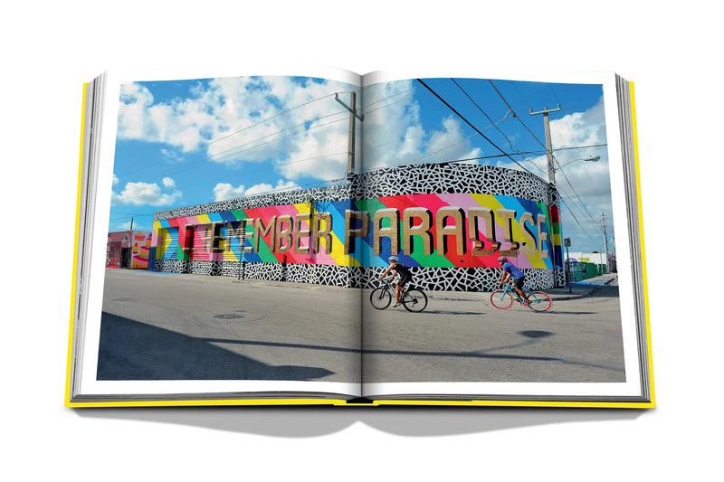 Libro de fotografía abierto con mural colorido y dos bicicletas frente a un muro