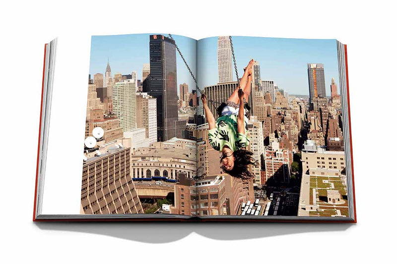 Libro abierto con fotografía de ciudad y persona levantando los brazos