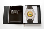 Libro de colección Patek Philippe abierto con reloj plateado de correa gris
