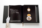 Libro de colección Patek Philippe abierto con reloj pequeño en vitrina
