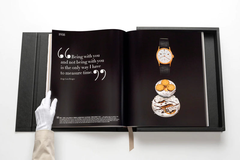 Libro de colección Patek Philippe abierto con reloj pequeño en vitrina