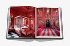 Libro abierto con dos fotos de dormitorio y pasillo con decoración roja y detalles ornamentales.