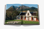 Libro abierto con foto exterior: edificio blanco con arcos, jardín y montañas al fondo.