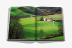 Libro Biarritz Vasca abierto; paisaje verde con ovejas y casa junto al camino.