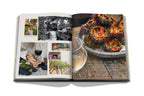 Libro de viajes y vino, páginas abiertas con fotos de cocina y plato con llamas