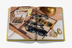 Libro abierto con gafas de colores sobre papel y accesorios sobre mesa de madera
