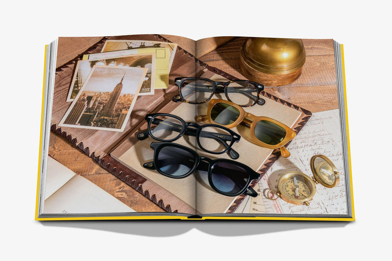 Libro abierto con gafas de colores sobre papel y accesorios sobre mesa de madera