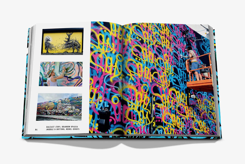 Libro abierto con fotos de murales y persona frente a pared de grafiti multicolor.