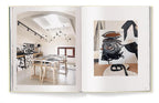 Libro abierto con foto de estudio blanco y mesa de trabajo con detalles de diseño