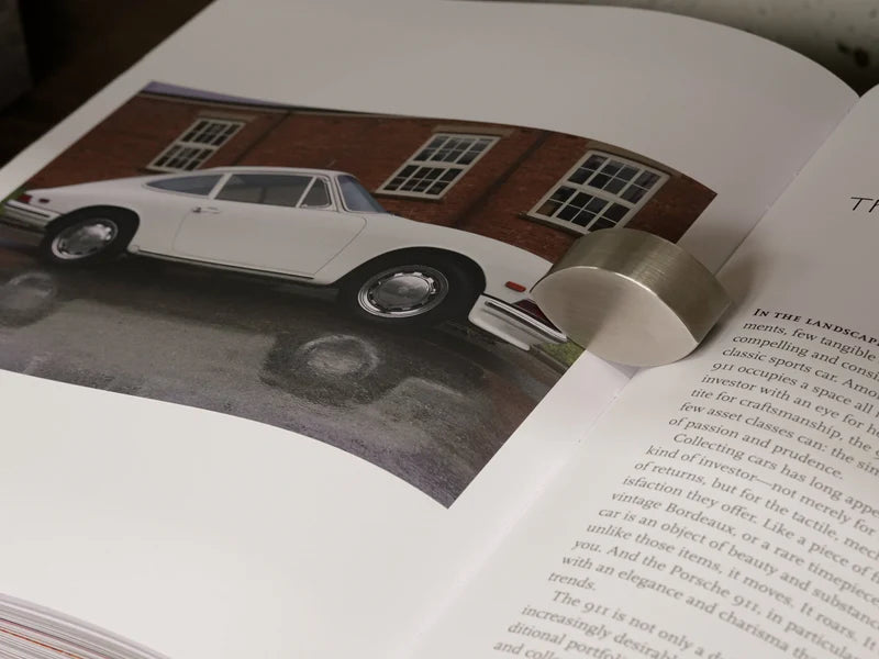 Libro abierto, foto lateral de auto blanco y párrafos de texto