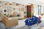 Sala con sofá beige, alfombra azul con flores y cuadros en la pared