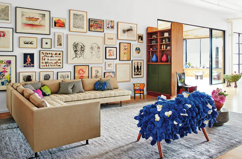 Sala con sofá beige, alfombra azul con flores y cuadros en la pared