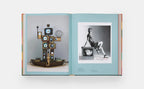 Libro abierto con fotografías de moda: página azul con objetos y foto en blanco y negro.