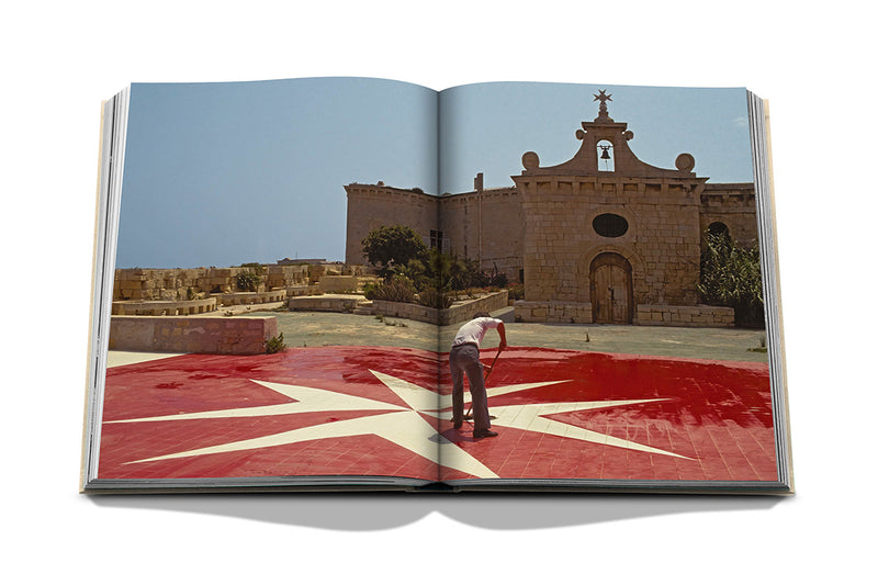 Libro abierto con foto de plaza y edificio de piedra visto al atardecer