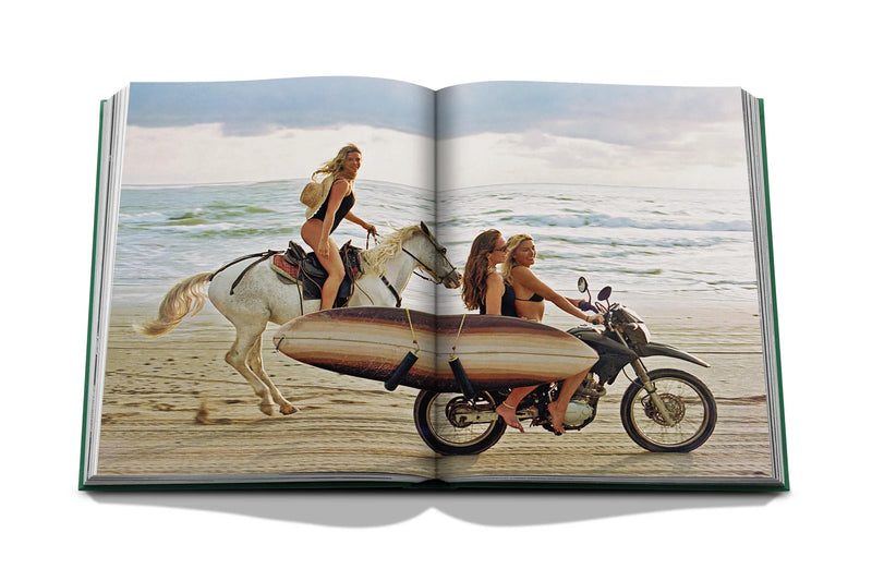 Libro abierto con foto en playa de personas sobre moto con tabla de surf