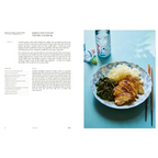 Libro de cocina japonesa abierto con receta a la izquierda y plato de carne con palillos