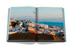 Libro abierto con foto panorámica de ciudad costera y mar al fondo