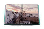 Libro abierto con foto de calles y viviendas blancas junto al mar