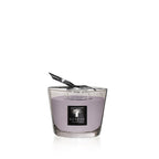 Vela en vaso de vidrio con cera morada y tapita negra con logotipo