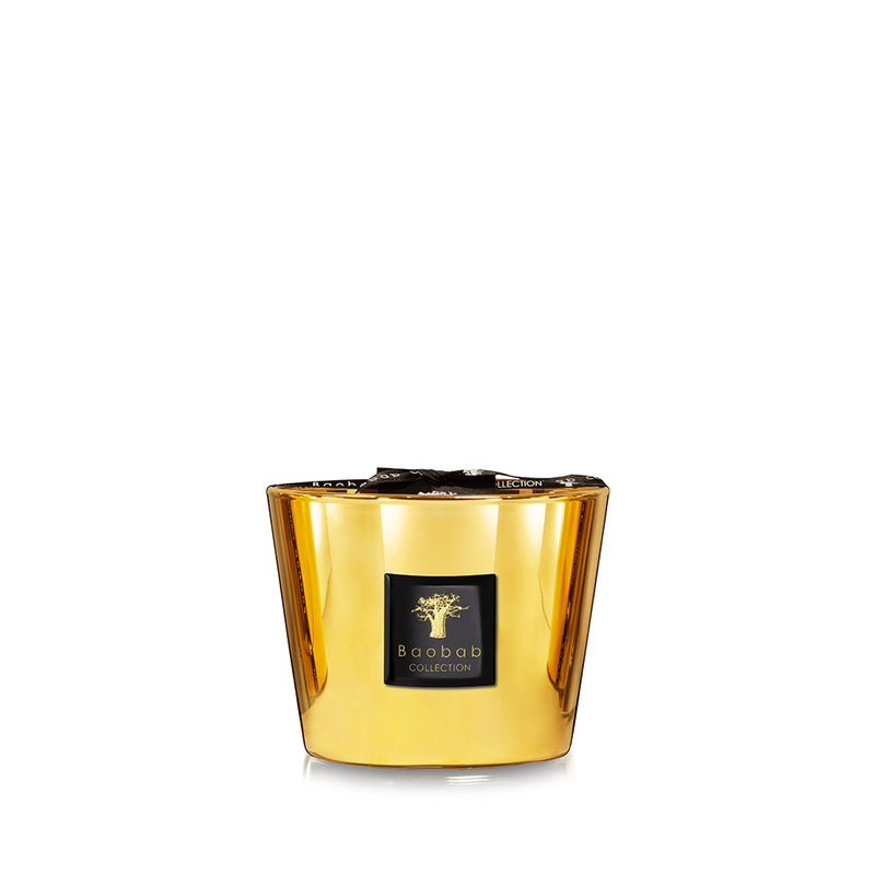 Vela en vaso de vidrio dorado con etiqueta Baobab Collection y cinta negra.