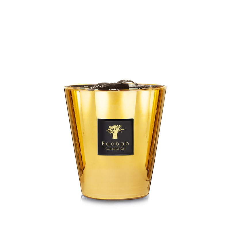 Vela en vaso de vidrio dorado con etiqueta Baobab Collection y cinta negra.