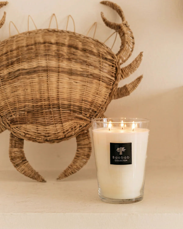 Vela en frasco de vidrio con cera blanca y etiqueta Baobab Collection, llama encendida