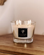 Vela en frasco de vidrio con cera blanca y etiqueta Baobab Collection, llamas visibles