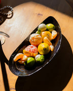 Cuenco forma mejillón de porcelana negra Marcel, lleno de frutas.