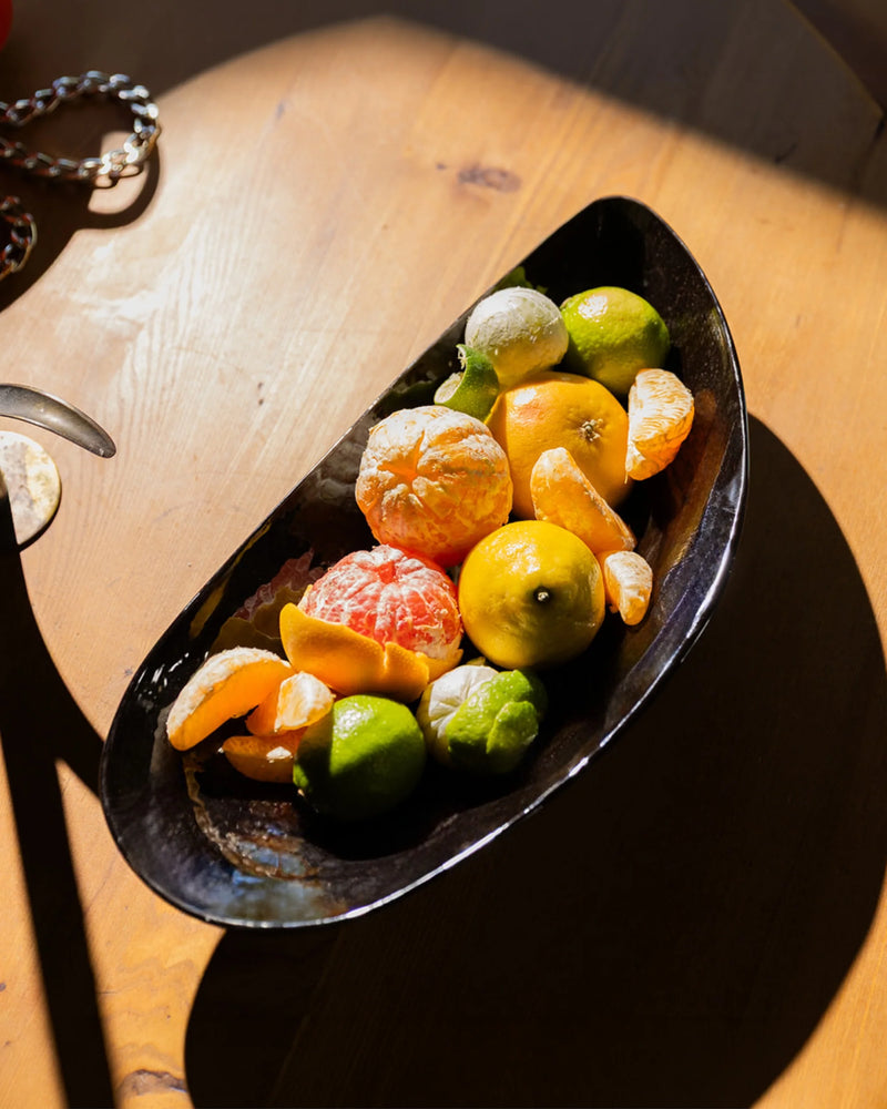 Cuenco forma mejillón de porcelana negra Marcel, lleno de frutas.