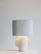 Lámpara de sobremesa beige claro con pantalla cilíndrica y base central tipo columna
