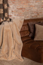 Beige Eco-Wool throw blanket draped over seating, soft sherpa texture